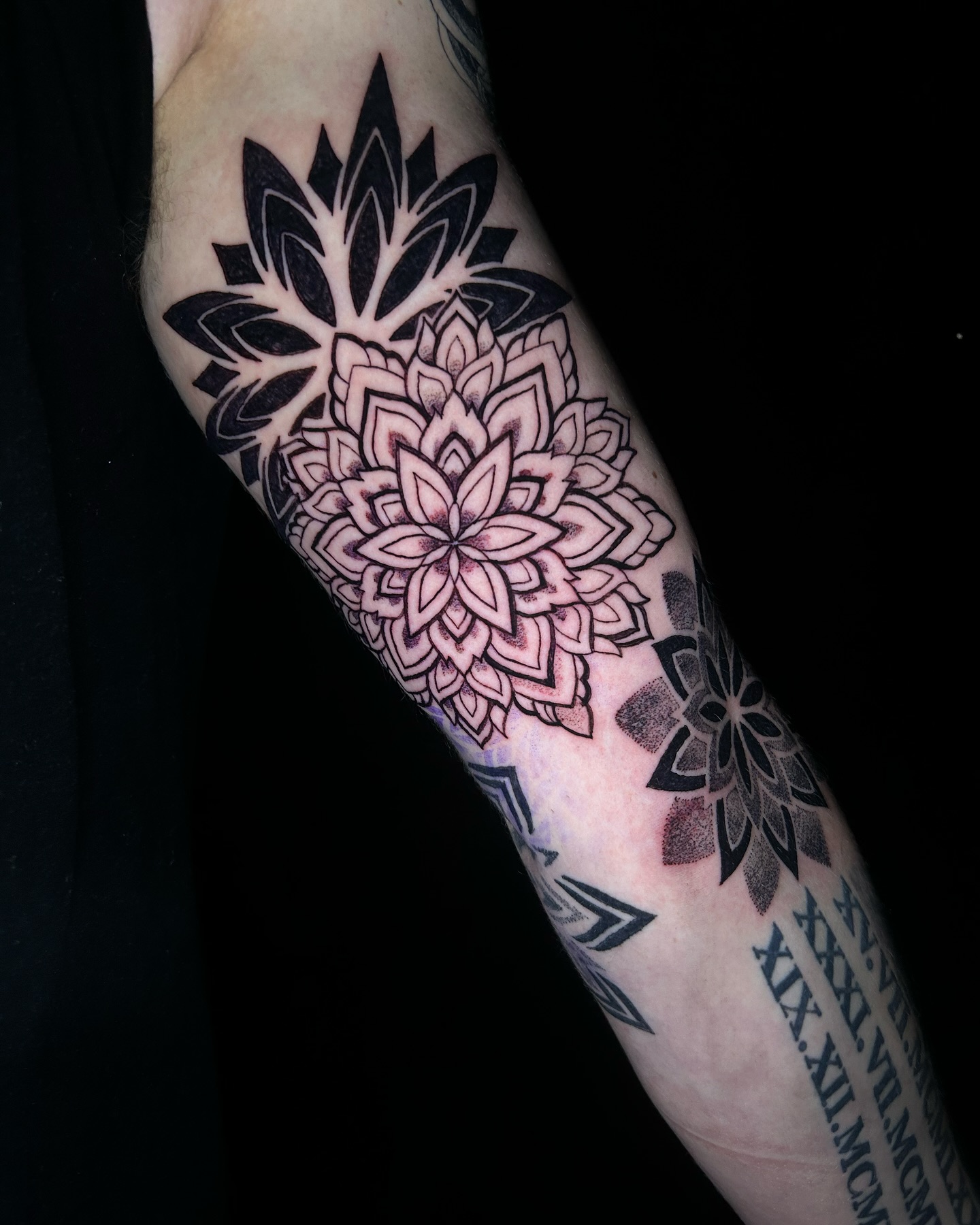 Blackwork en dotwork mandala sleeve met romeinse cijfers op een onderarm